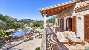 A stone building with a pool, lounge chairs, and a view of the mountains. - Villa in Búger perfect for children with swimming pool, paddle court and large garden (Búger)