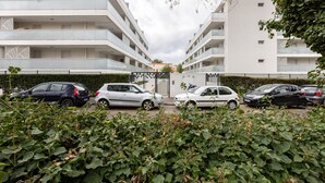 Ein mehrstöckiges Wohngebäude mit Balkonen, einem verschlossenen Eingangsbereich und geparkten Autos.