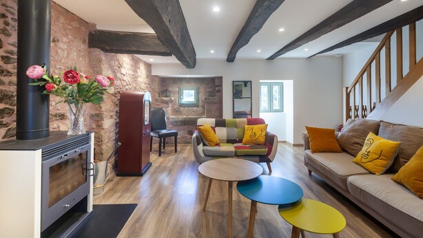 Ein gemütliches Wohnzimmer mit Kamin, einer Couch mit bunten Kissen und Holzboden.