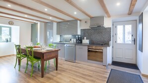 Eine moderne Küche mit Holzbalken, einer Essecke mit grünen Stühlen und einer gefliesten Rückwand.