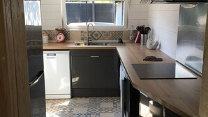 Eine kleine Küche mit Fenster, Spüle, Kühlschrank und Geschirrspüler.