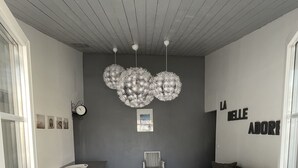 Ein modernes Wohnzimmer mit grauem Sofa, weißem Couchtisch und einem gestreiften Sessel. Eine Wandleuchte und ein gerahmtes Bild befinden sich über dem Couchtisch.