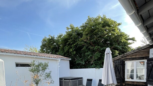 Eine Terrasse mit Tisch und Stühlen, ein kleiner Garten und ein Holzzaun.