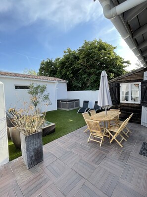 A patio with a table and chairs, a small garden, and a wooden fence. - 3-star vacation home La Belle Adorée, 2 steps from the beach. (La Couarde-sur-Mer)