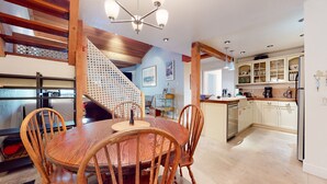 Eine moderne Küche mit Holzschränken, einem Esstisch mit Stühlen und einer Treppe, die in eine obere Ebene führt.