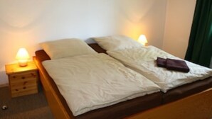 Un letto singolo con lenzuola bianche, due lampade ai lati e un comodino in legno.
