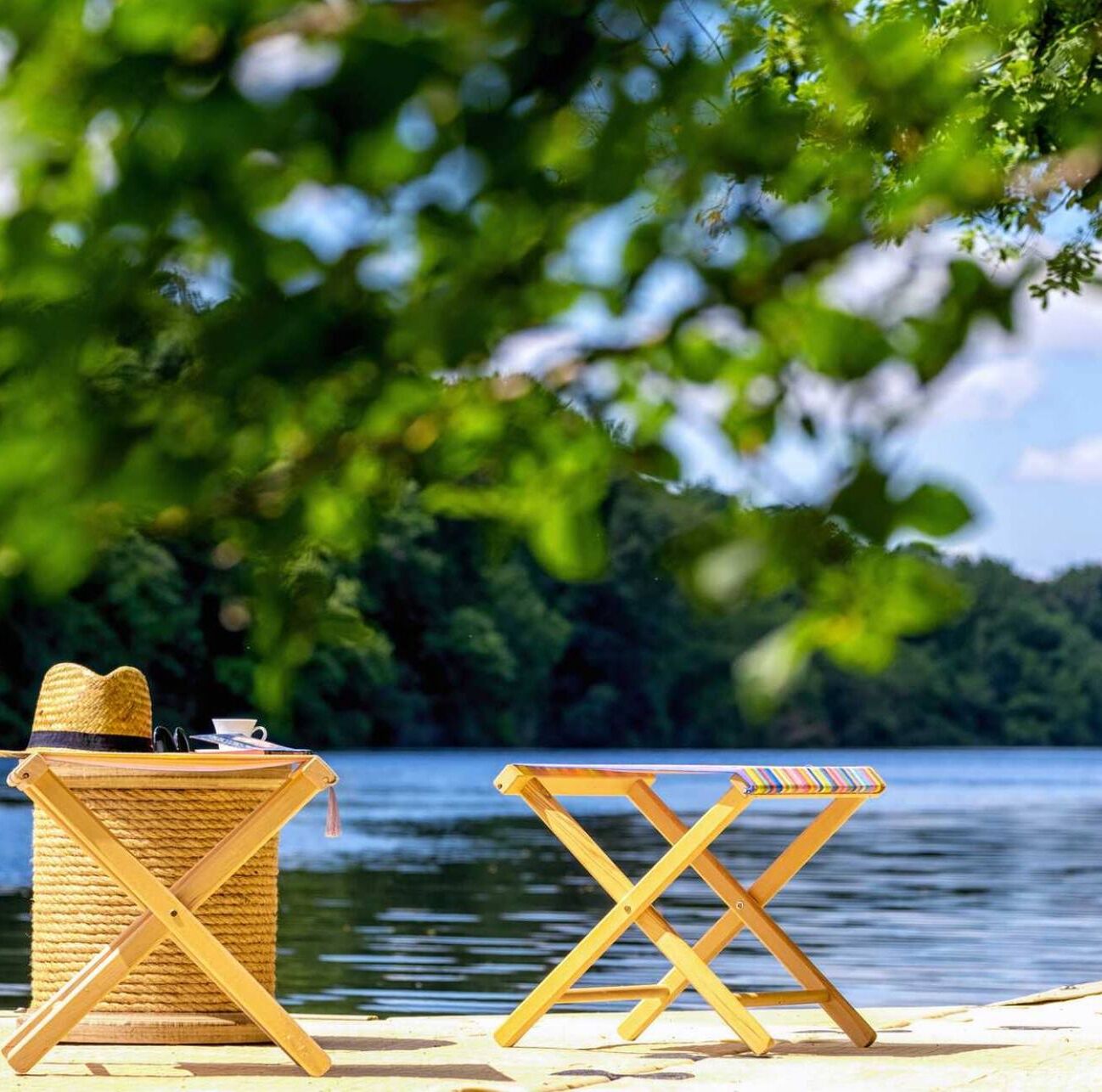 A beach setting with a wicker basket and a wooden folding chair.