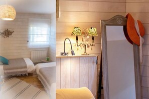 Une chambre confortable avec deux lits, une fenêtre avec des stores, une lampe suspendue et un miroir orné d’un chapeau décoratif.