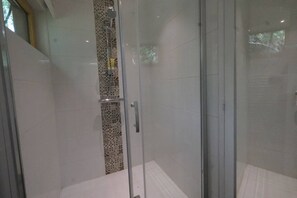 Un área de ducha con paredes de azulejos decorativos y suelo de baldosas lisas.