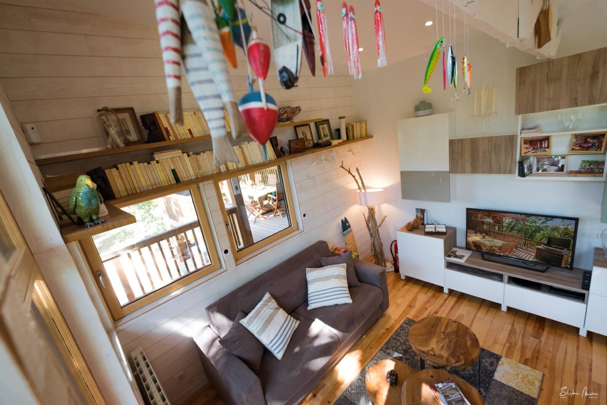 Ein gemütliches Wohnzimmer mit einer braunen Couch, einem Fernseher und Holzboden.