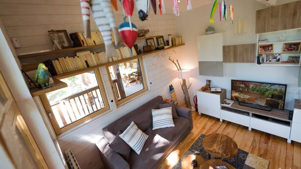 Una sala de estar acogedora con un sofá marrón, televisión y suelo de madera.
