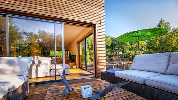 A modern outdoor seating area with wicker sofas and a wooden deck.