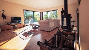 A spacious living room with a large window, a fireplace, a sofa, and a television.