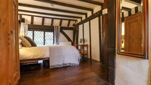 A bedroom with a bed, a wooden wardrobe, a small table with a chair, and a window with curtains. - Church View (Rye)