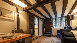 A cozy room with a wooden dining table set for two, a comfortable sofa, and a large window with a view of greenery. - Church View (Rye)