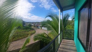 A balcony with a view of a rural landscape, including palm trees and a dirt road. - Breeze #4 - Brisas Griegas Vacations (Quepos)