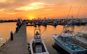 A marina with boats docked at the pier during sunset.