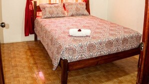 A bedroom with a wooden bed, red curtains, and a patterned bedspread. - Breeze #4 - Brisas Griegas Vacations (Quepos)