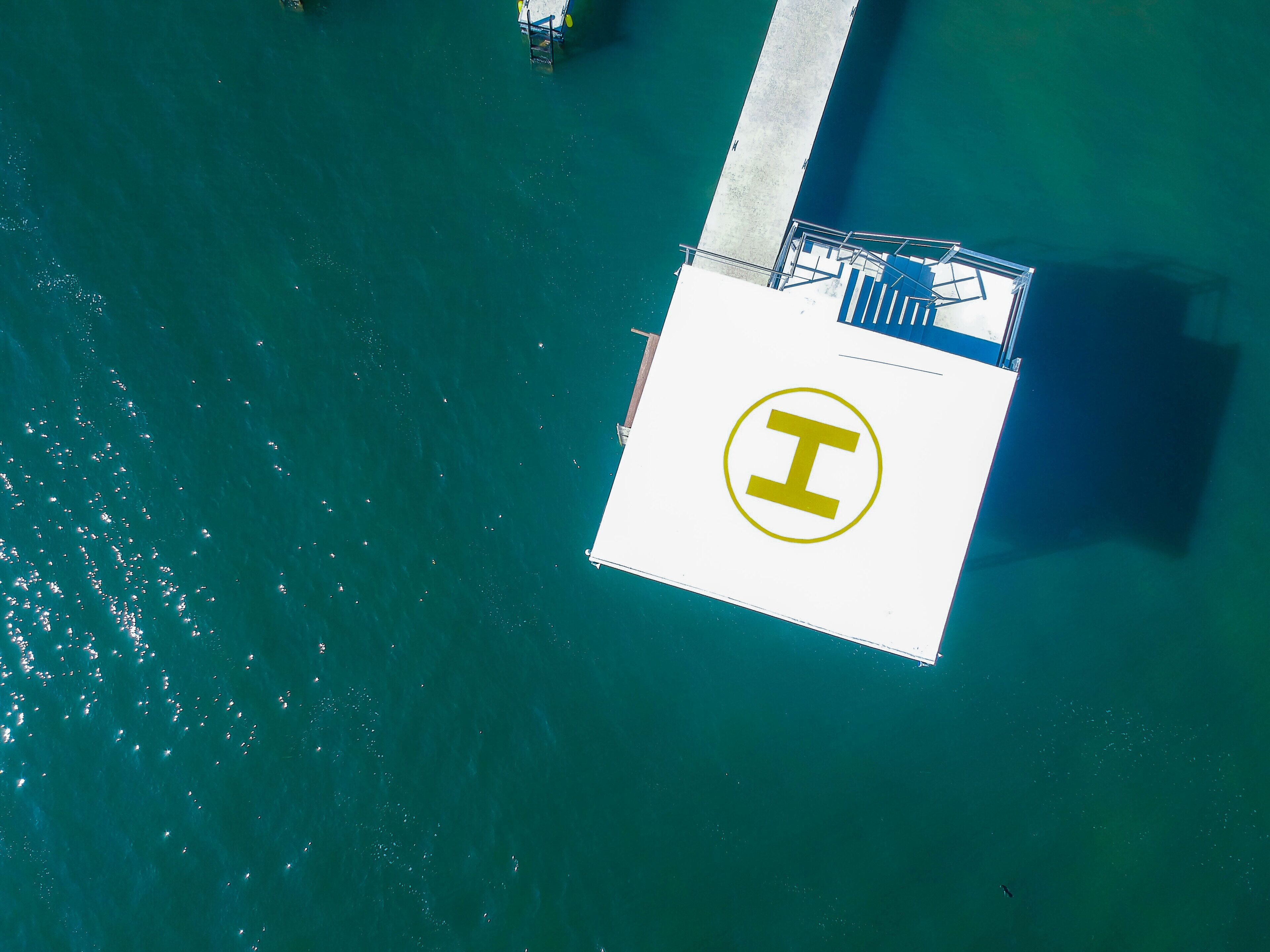 Vue aérienne d’un quai sur lequel se trouve une grande plateforme blanche, ornée d’un logo jaune en forme de « I » bien visible.