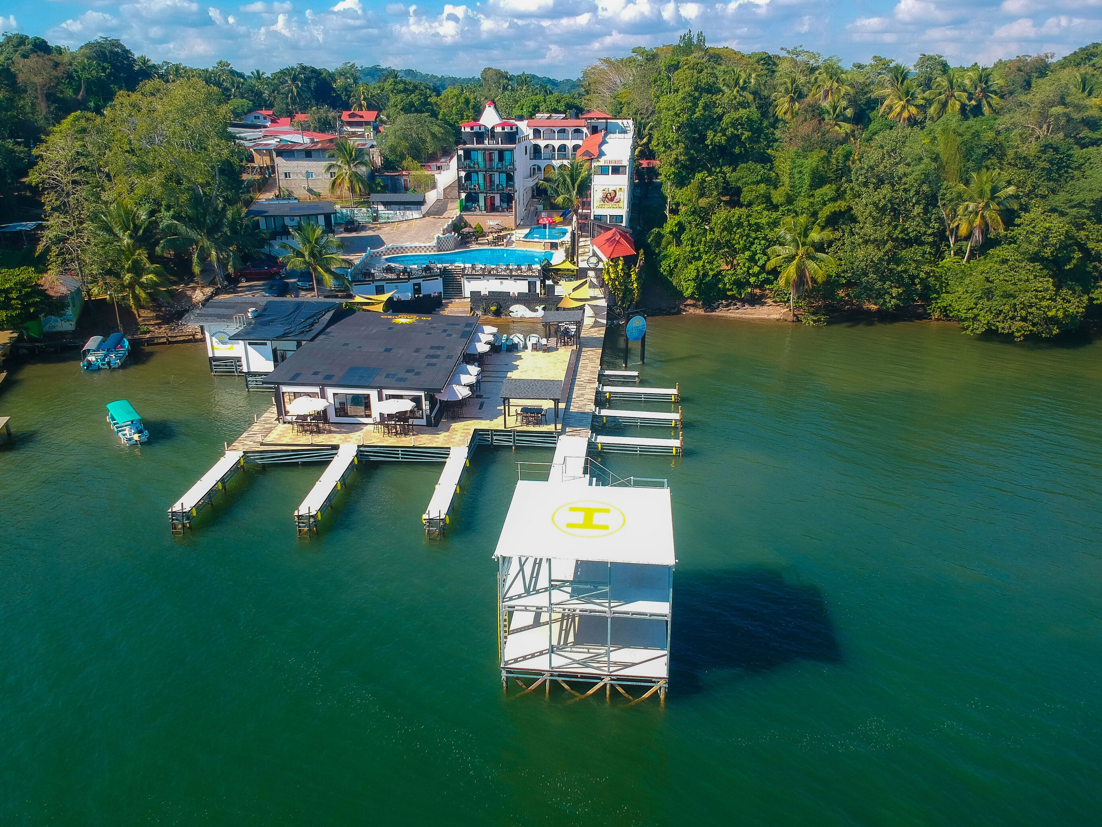 An aerial view of a waterfront hotel with multiple buildings, a swimming pool, and docked boats.