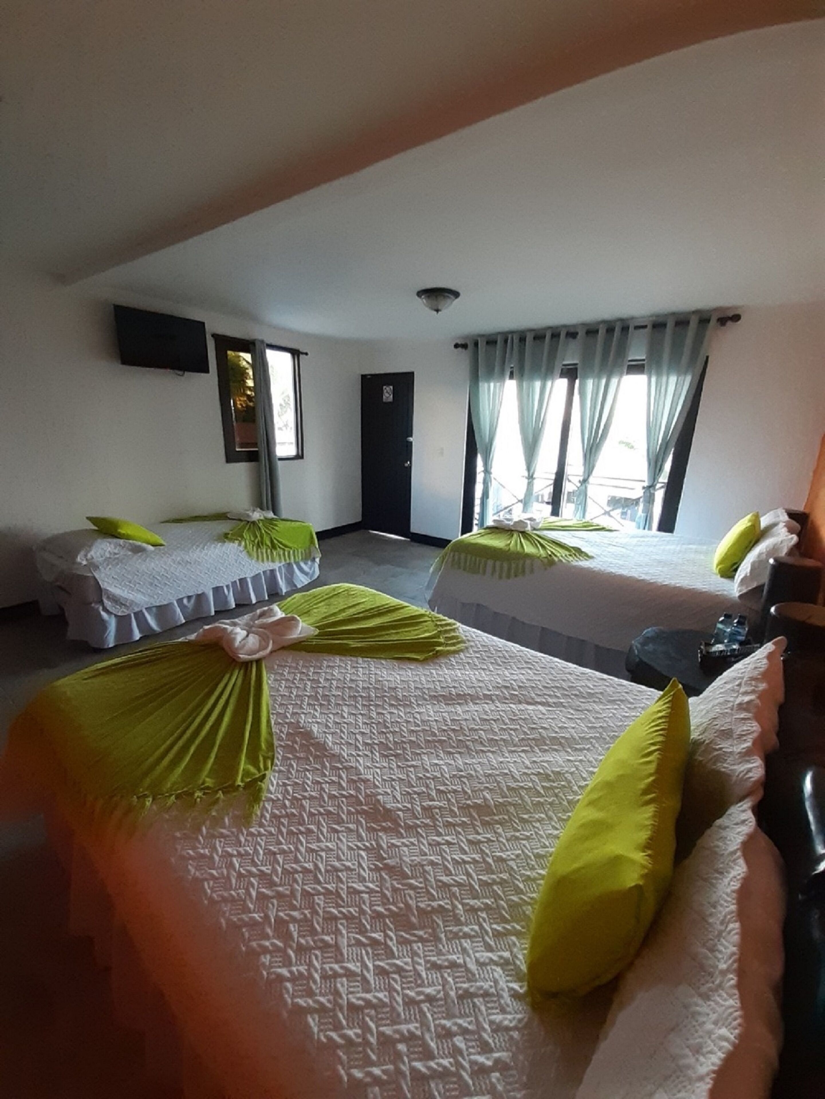 Una habitación de hotel con dos camas, un televisor montado en la pared y una puerta.