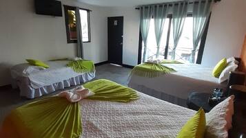Una habitación de hotel con dos camas, un televisor montado en la pared y una puerta.