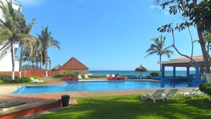 A pool area with lounge chairs, a small hut, and a view of the ocean. - Casas RDM (Mazatlán)