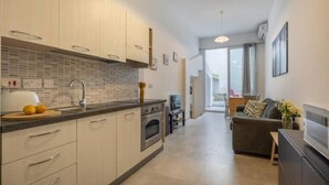 A modern kitchen with a large island, built-in oven, and a dining area with a sofa and table.