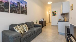 A living room with a gray sofa, a small side table, and a cityscape painting on the wall.