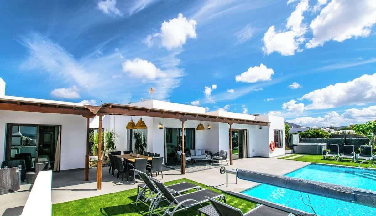 A modern outdoor pool area with a patio, lounge chairs, and a dining area.