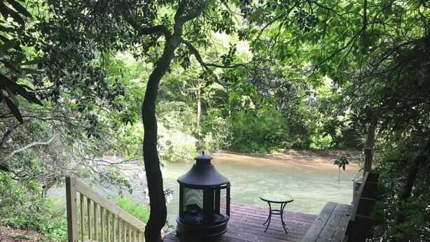 Una terraza de madera con un farol, un banco y vistas a un río.