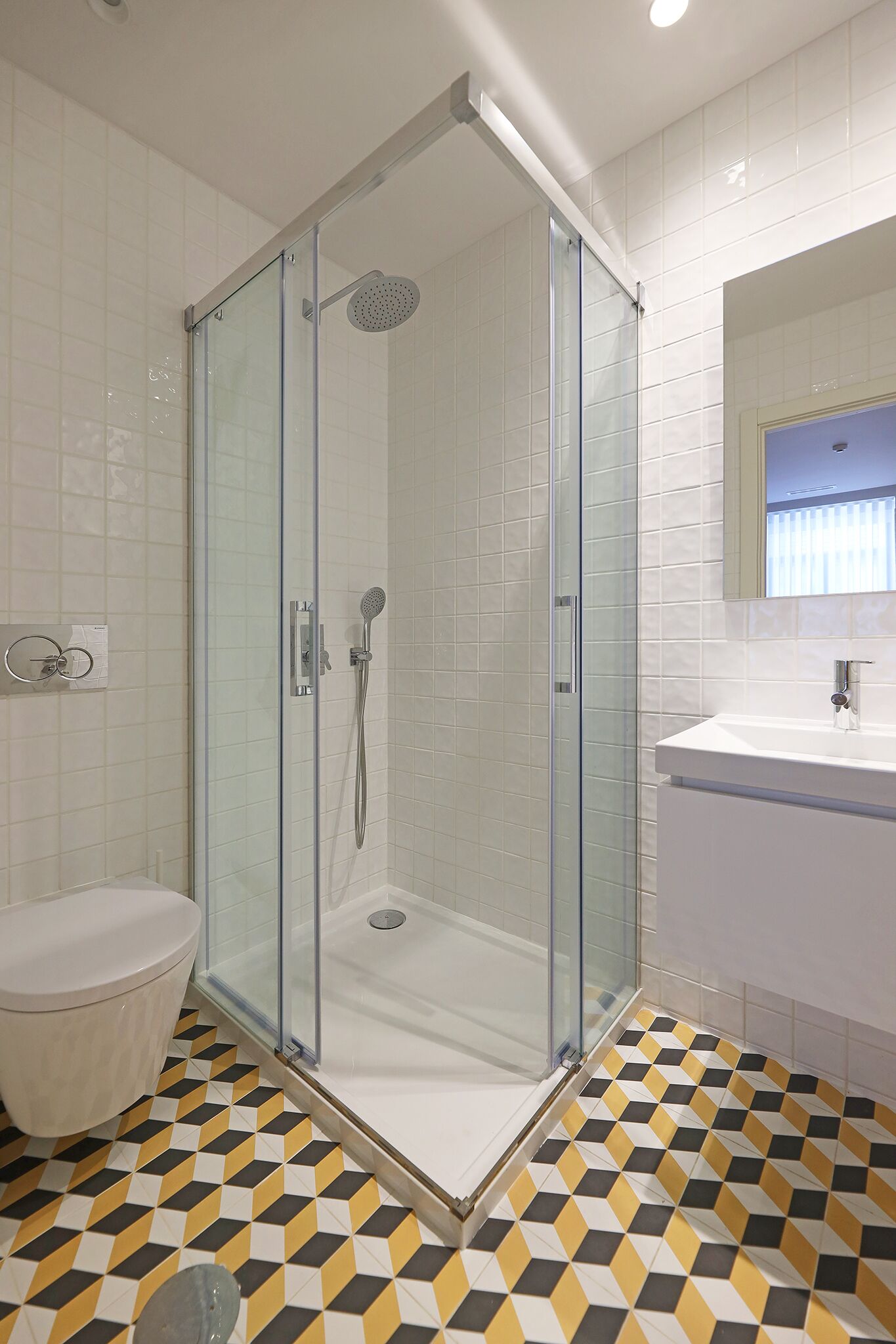 A modern bathroom with a glass-enclosed shower, a white toilet, and a sink with a mirror.