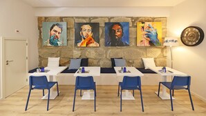 A room with a stone wall, four paintings, a clock, and a table with chairs. - FLH Porto Downtown GuestHouse (Porto)
