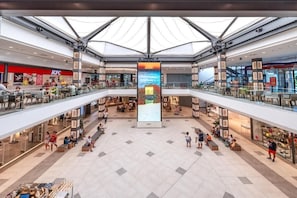 Un centro comercial de varios niveles con un atrio central, escaleras mecánicas y diversas tiendas.