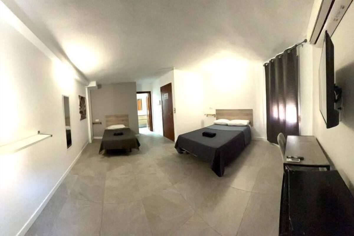 A hotel room with two beds, a desk, and a television.