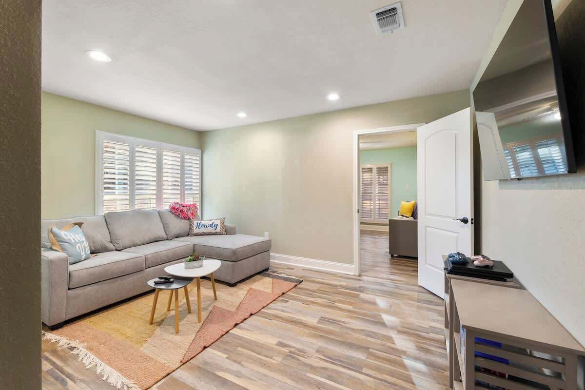 A modern living room with a grey sofa, a small round table, and a wooden floor.