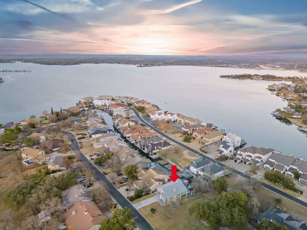 An aerial view of a residential area with houses, roads, and a body of water.