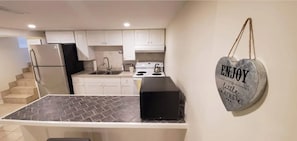 Enjoy the little things in this cozy kitchen with a heart-shaped sign, complete with a refrigerator, stove, sink, and kettle.