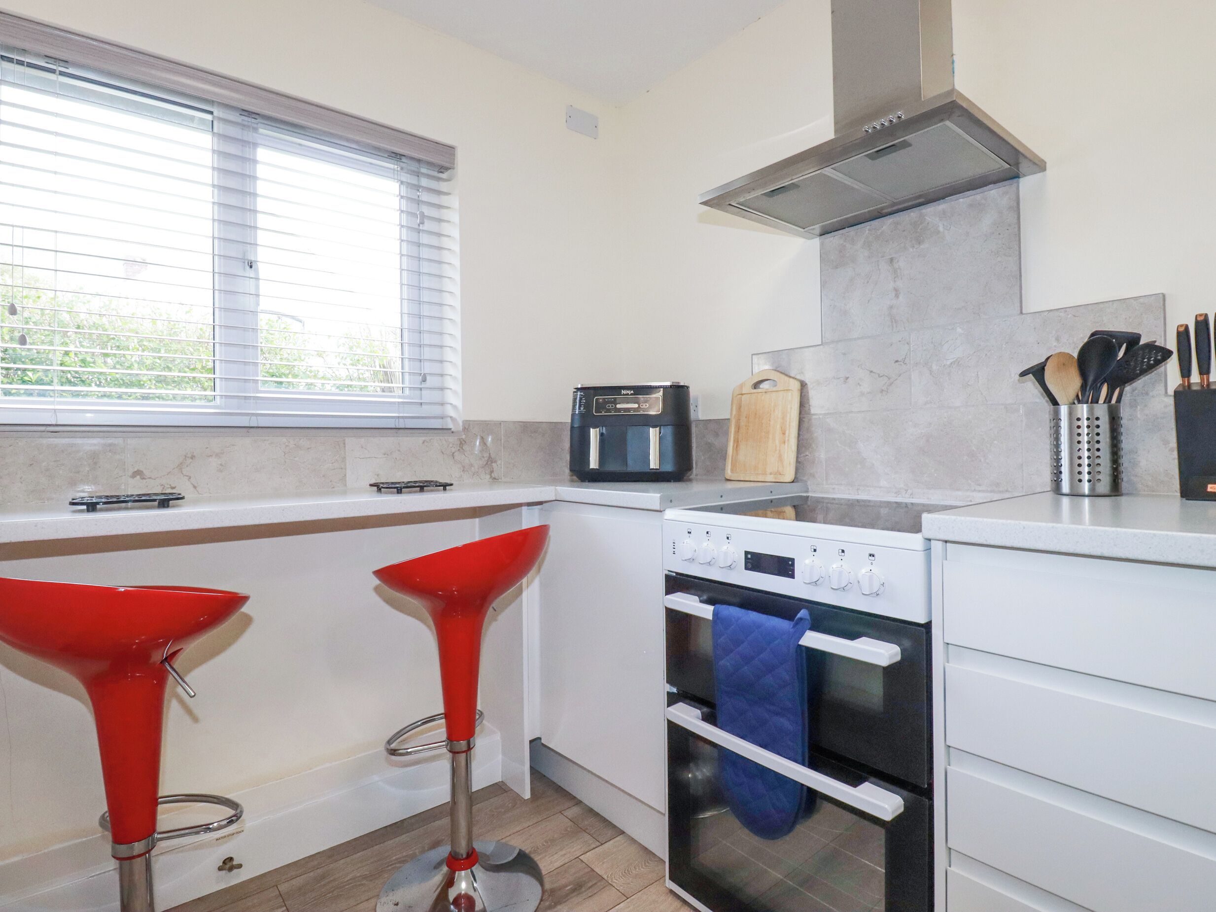 A modern kitchen with a built-in oven, a coffee maker, and a cutting board on the countertop.