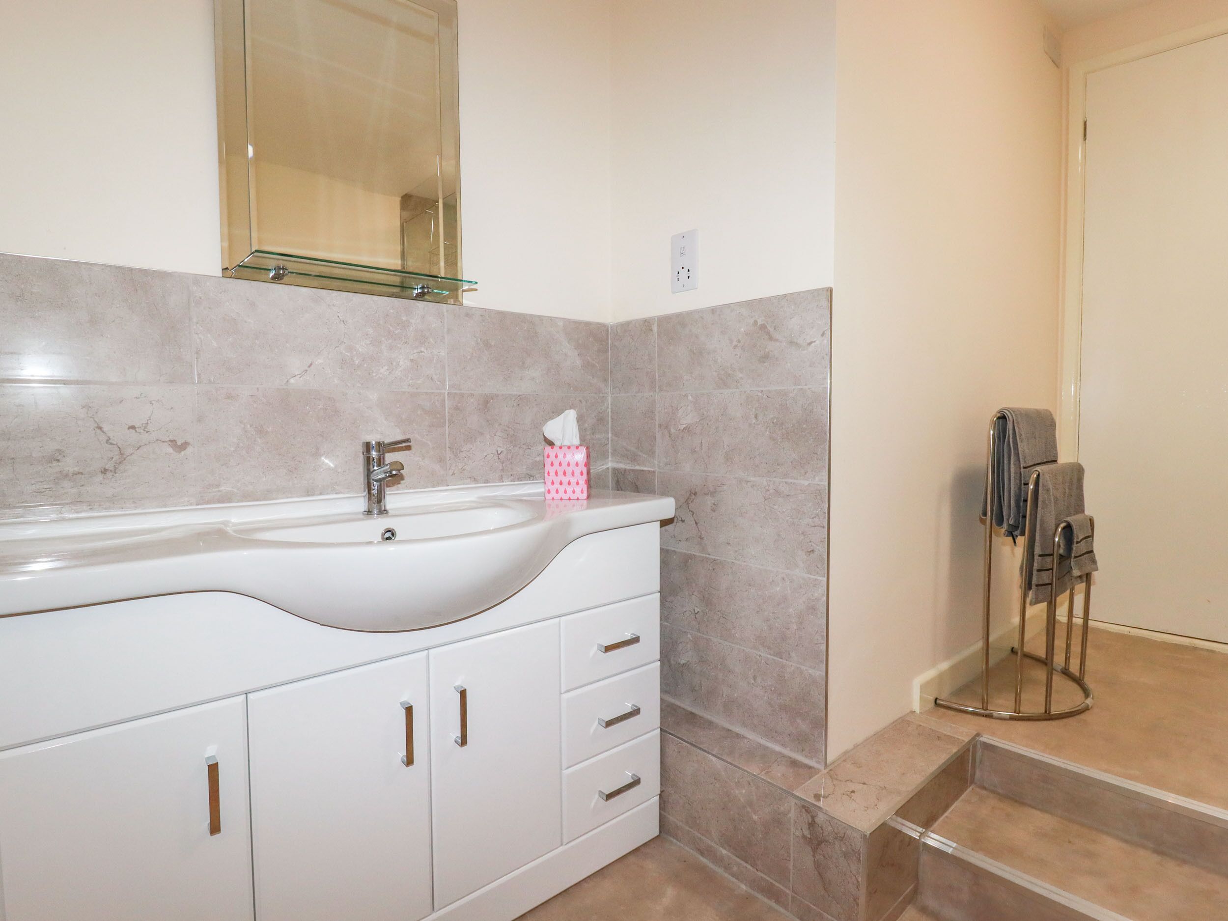 A bathroom with a white vanity, a mirror, and a towel rack.