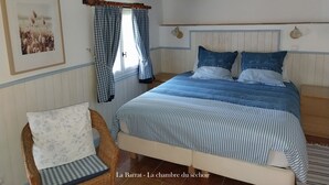 A bedroom with a bed, a chair, a window with curtains, and a wall-mounted light fixture. - Le Séchoir, Cottage of 75 m2 for 2 people with swimming pool, large park (MONMARVES)