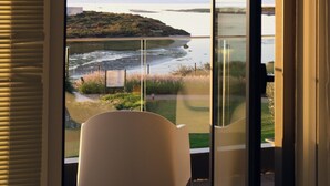 Quarto com uma janela grande com vista para a praia e o oceano.