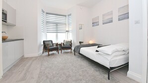 A bedroom with a bed, a desk, a chair, and a window with blinds. - F69 21 · London Studios Shepherds Bush near Central Line (London)
