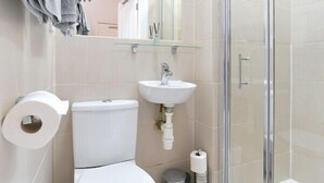 A modern bathroom with a toilet, sink, and glass shower enclosure. - F69 21 · London Studios Shepherds Bush near Central Line (London)