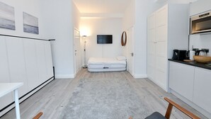 A compact room with a bed, a kitchenette, a flat-screen TV, and a small table. - F69 21 · London Studios Shepherds Bush near Central Line (London)