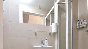 Un baño con inodoro, lavamanos y cabina de ducha de vidrio.