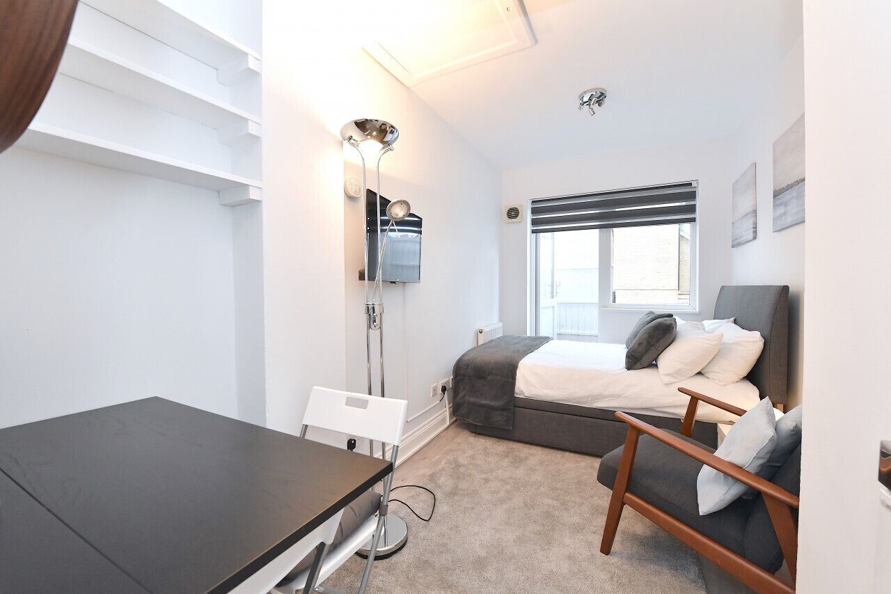 Une chambre à coucher moderne avec un lit, une table de chevet, une chaise et un bureau.