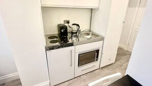 Una kitchenette compacta con cafetera, horno pequeño y lavabo.