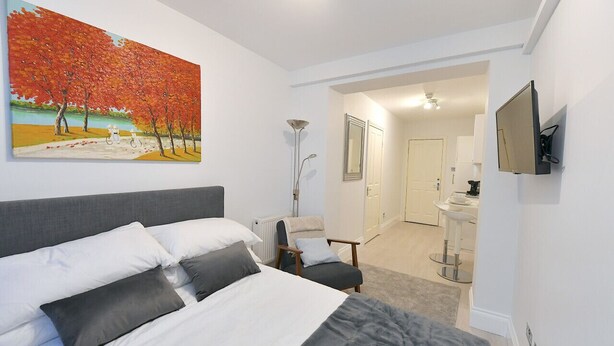 Une chambre à coucher moderne avec un grand lit, une chaise, un bureau et un tableau accroché au mur.