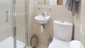 Une salle de bain moderne avec une douche à parois de verre, un lavabo blanc et des toilettes.